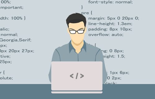 Programmer sitting at a laptop with a backdrop of CSS code